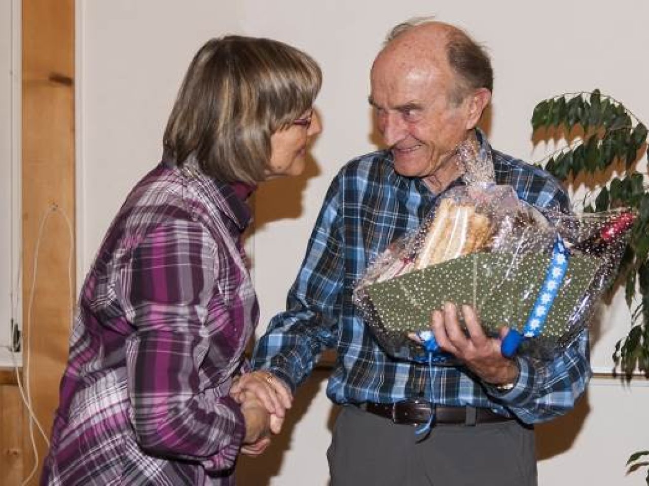 Rückblick auf das Jubiläumsfest vom 4. Dezember 2015 Eine Frau gratuliert engagiert einem sichtlich gerührten Vereinsgründer